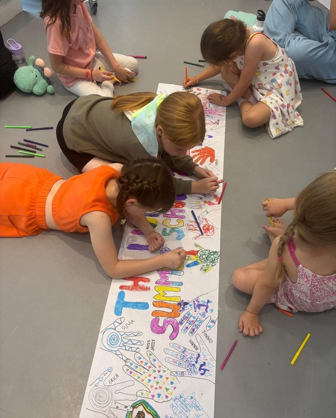 Children painting a giant summer school banner on the studio floor