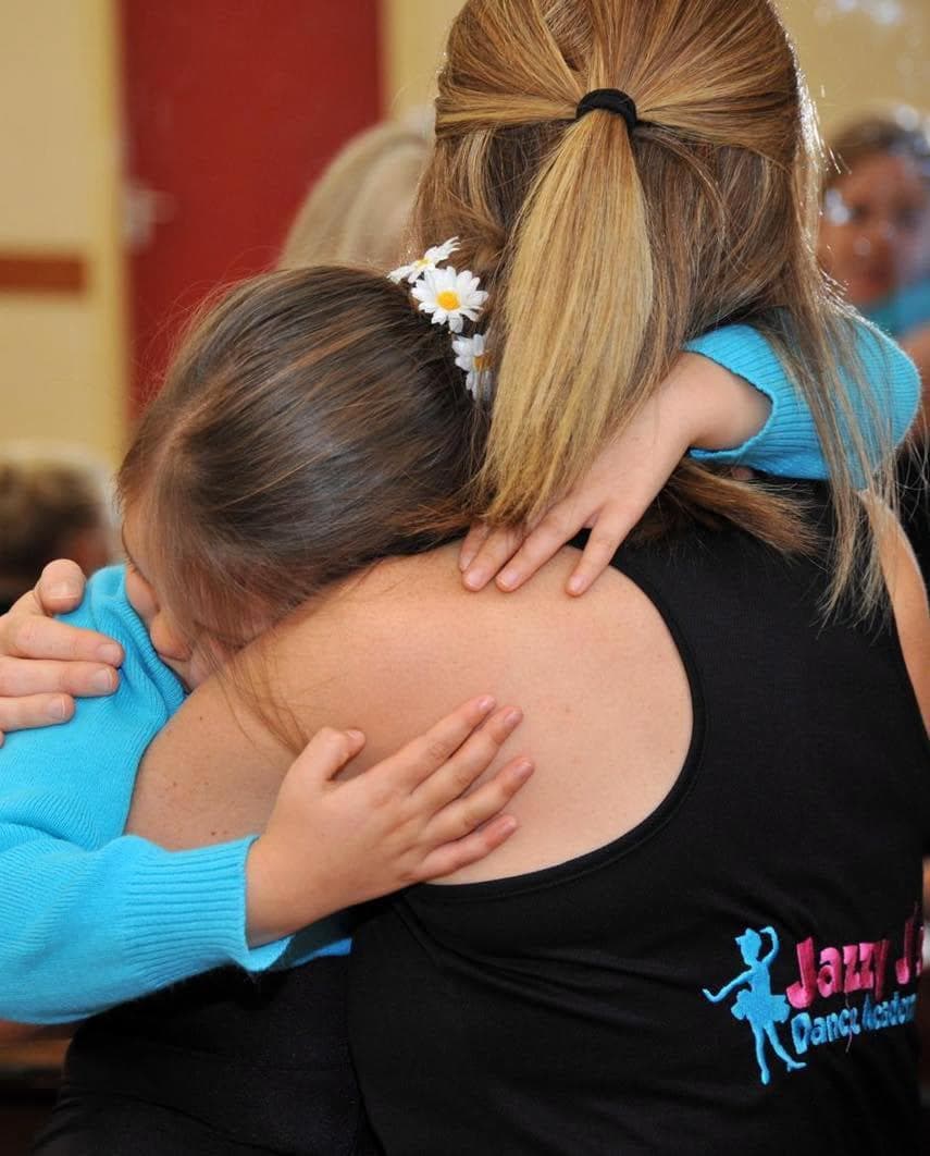 A young pupil hugging her teacher