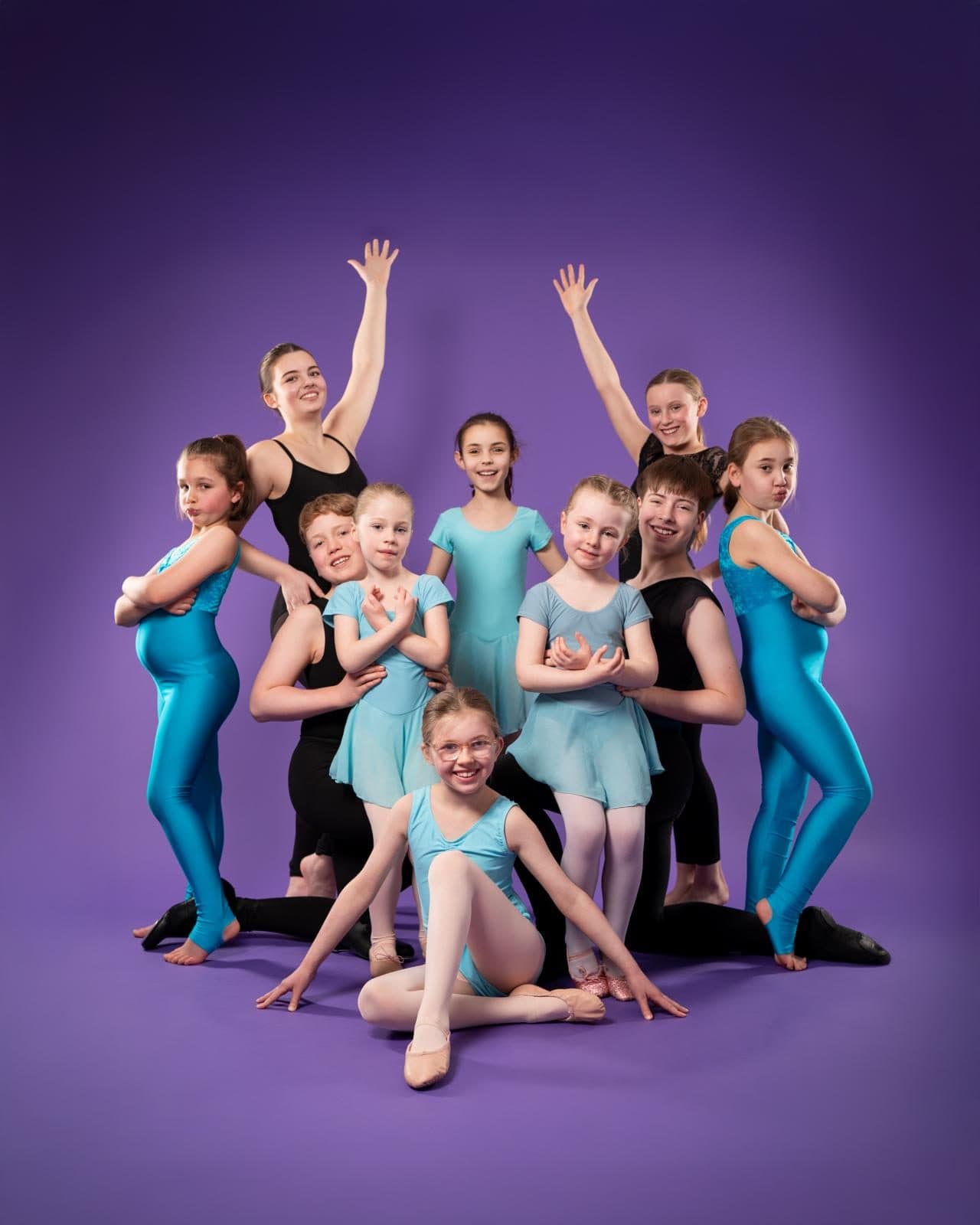 A group of Jazzy J's dancers posing together on a purple backdrop