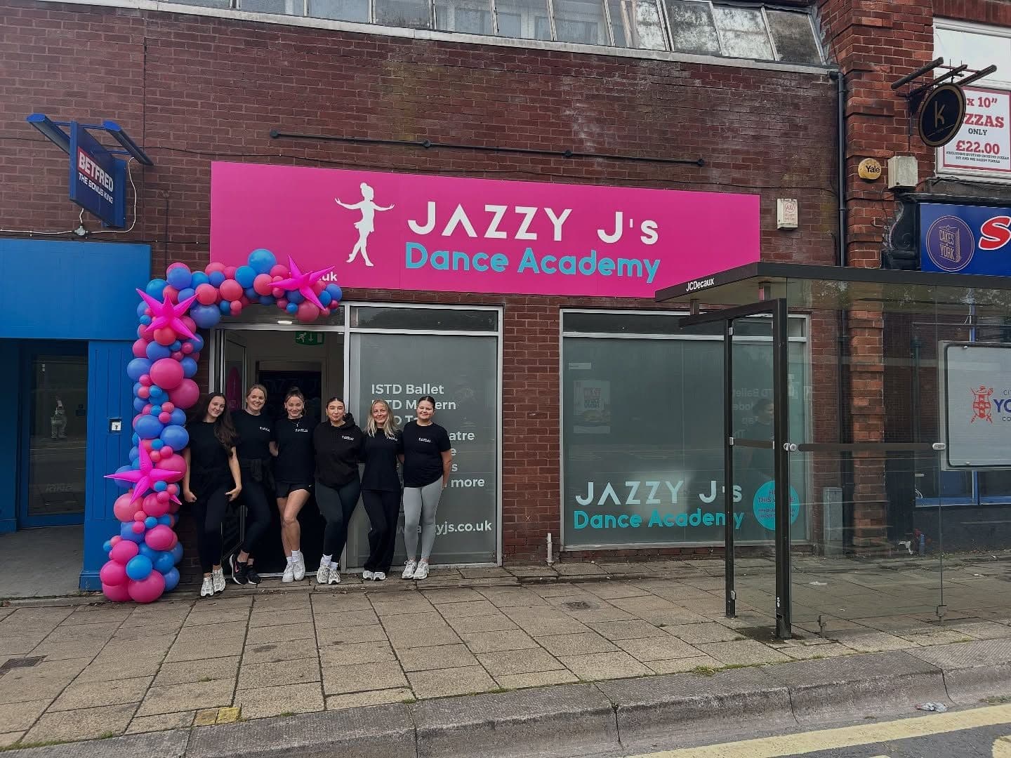 The pink Jazzy J's shopfront at Acomb Court with a balloon arch and the teaching team outside