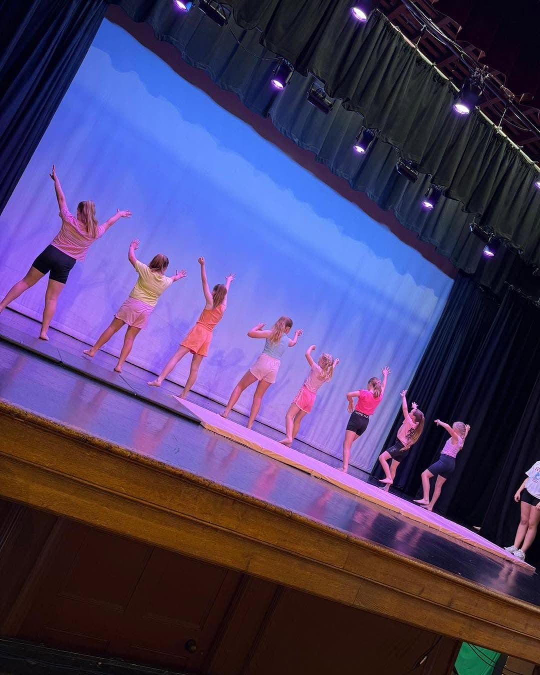 Dancers in bright casual outfits performing a pop routine on stage