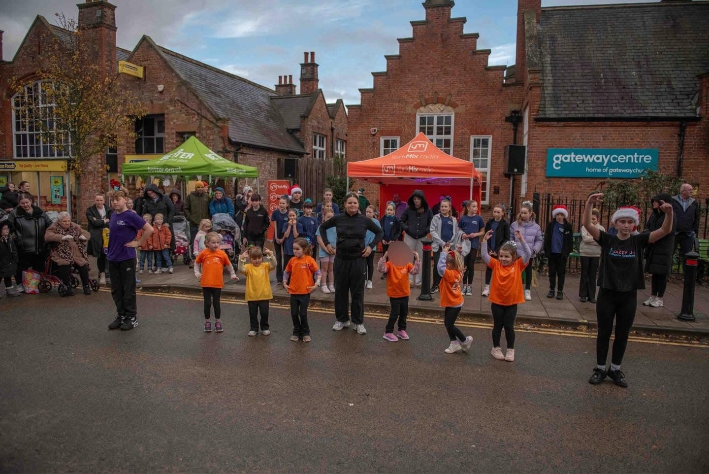 Pupils in orange T-shirts performing in the street in Acomb